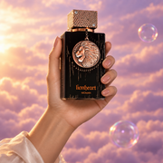 Una mano sostiene el frasco de Club de Nuit Lionheart Woman de Armaf entre nubes rosadas.