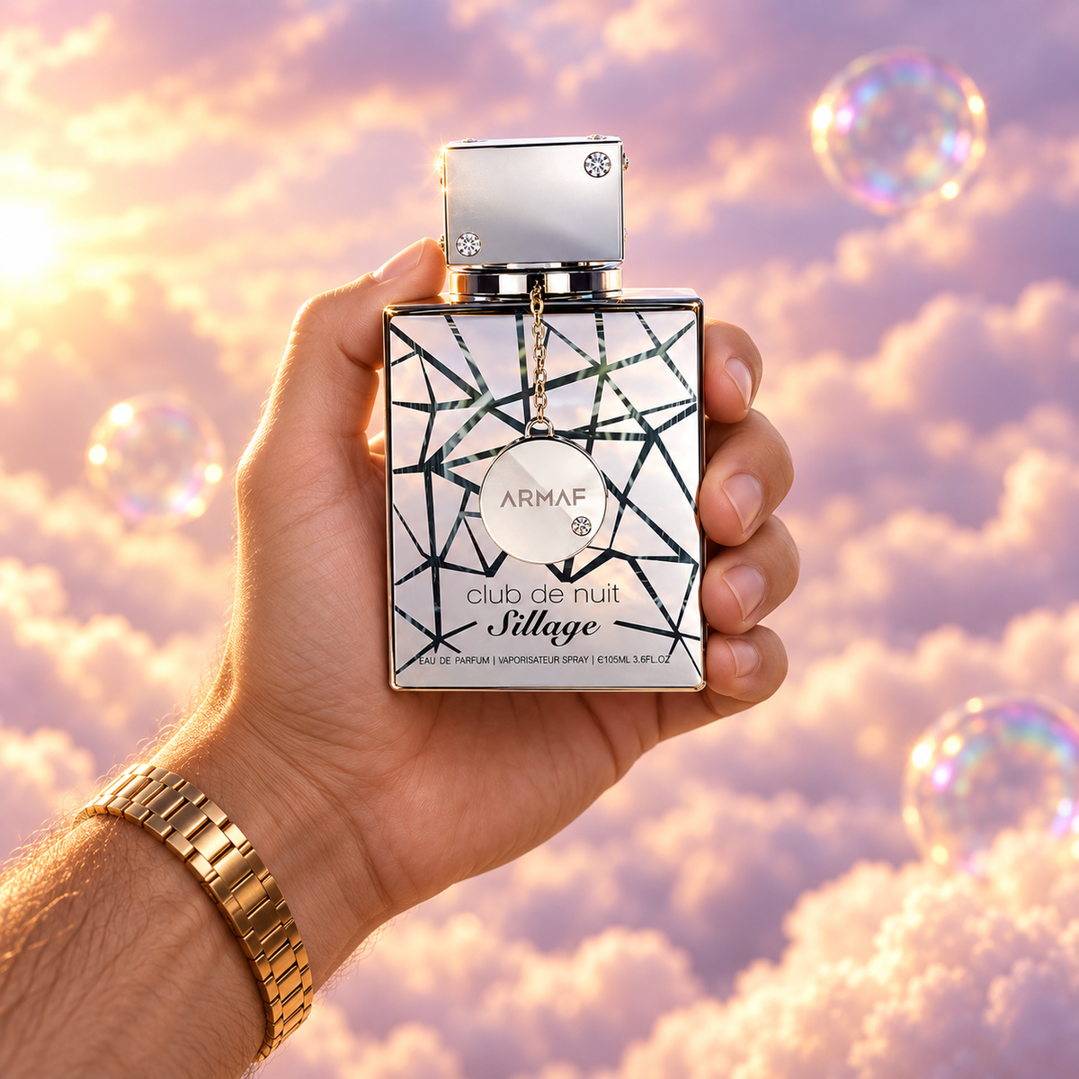 Una mano sostiene el frasco de Club de Nuit Sillage de Armaf entre nubes rosadas.