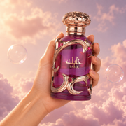 Una mano sostiene el frasco de Habik de Lattafa entre nubes rosadas.