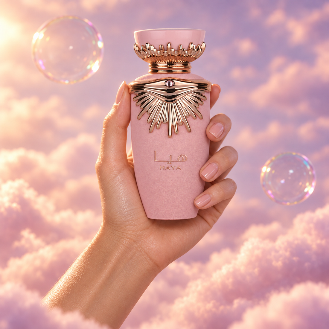 Una mano sostiene el frasco de Haya de Lattafa entre nubes rosadas.
