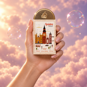 A hand holds the bottle of London The City of Contrast by Lattafa among pink clouds.